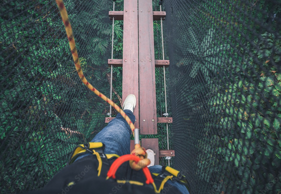 Risk management in Cyprus symbolized by a person safely navigating a suspension bridge - NexusInc