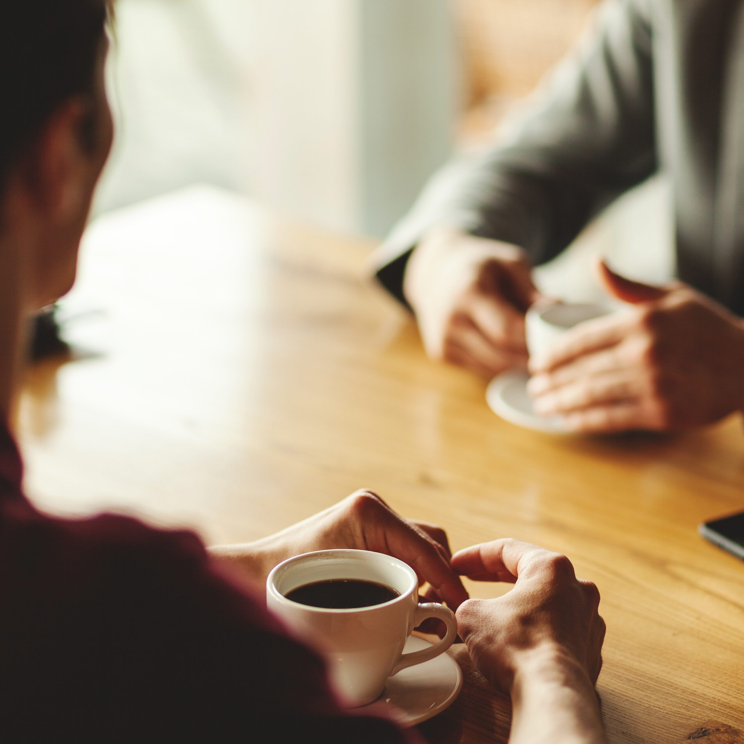 Insurance agent in Cyprus advising client over coffee about the benefits of insurance - NexusInc